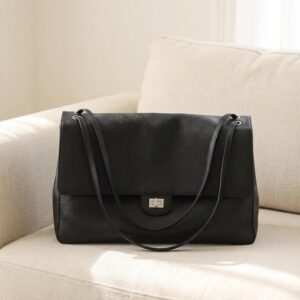 The Kensington black leather flap bag styled on a sofa